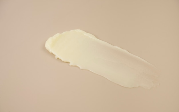 Produits cosmétiques texture jaune crémeux tache fond beige nude. la texture du masque capillaire, de la crème, du gommage des cosmétiques naturels.