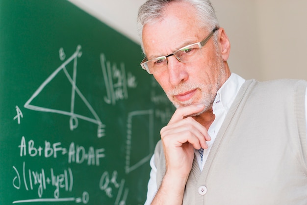 Photo gratuite professeur âgé, debout près d'un tableau dans une salle de classe