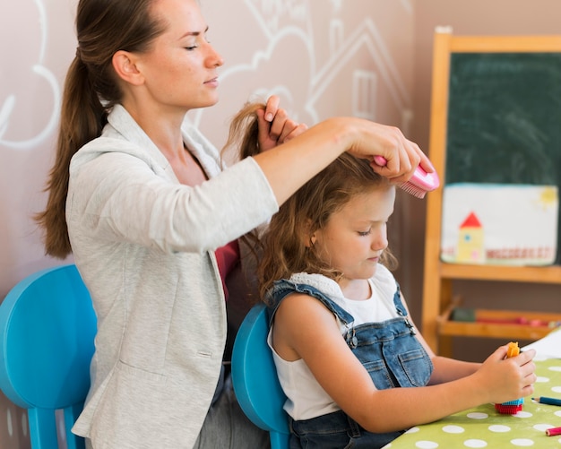 Professeur de coup moyen se brosser les cheveux de la fille