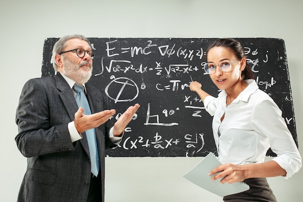 Photo gratuite professeur masculin et jeune femme contre le tableau noir en classe
