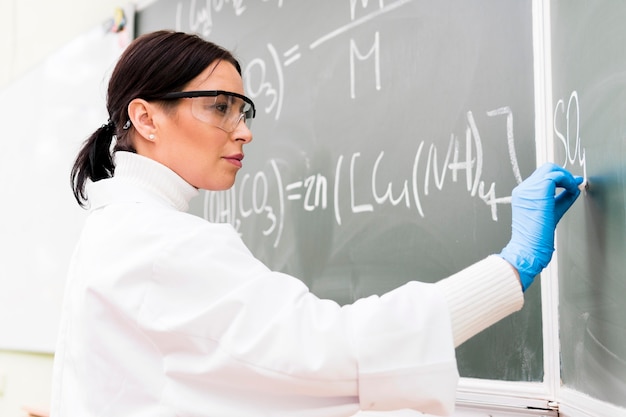 Photo gratuite professeur de sciences écrit sur tableau noir