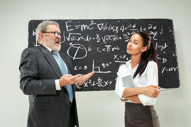 Professeur de sexe masculin et jeune femme contre le tableau noir en classe