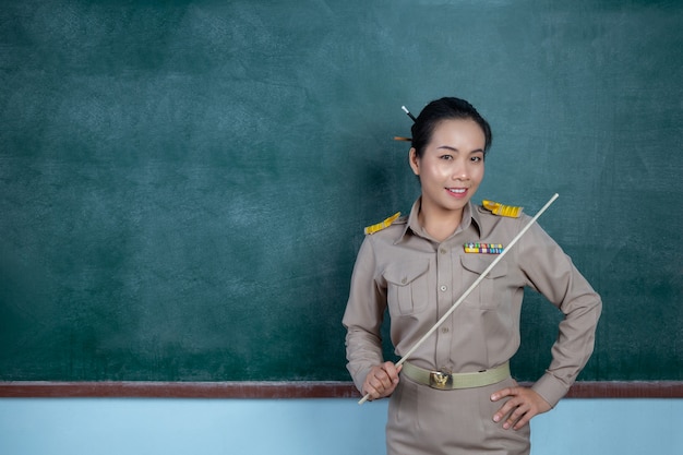 Professeur thaïlandais heureux en tenue officielle posant devant le tableau noir