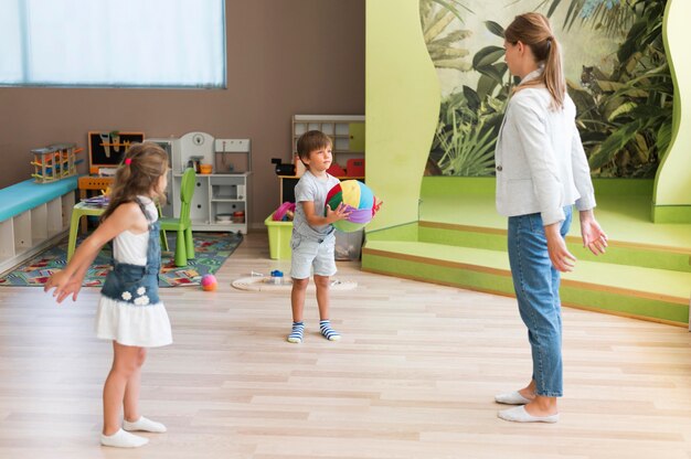 Professeur de tir complet et enfants jouant avec un ballon