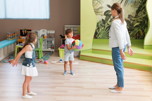 Professeur de tir complet et enfants jouant avec un ballon