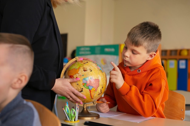 Photo gratuite professeur de vue de côté aidant les enfants