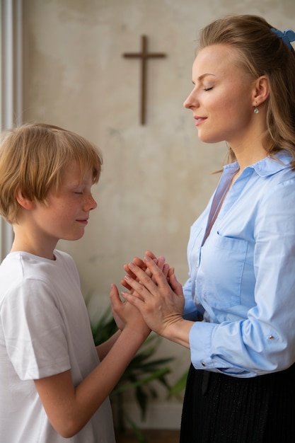 Professeur de vue de côté et enfant priant ensemble