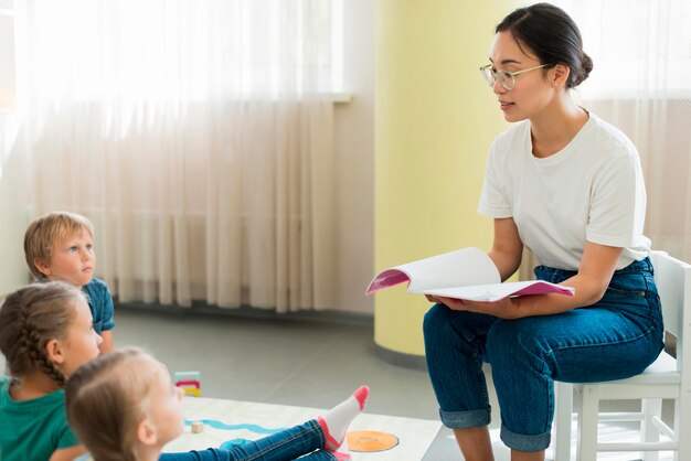 Professeur de vue latérale lisant une histoire à ses élèves