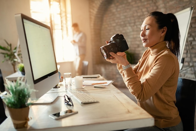 Professionnel du design asiatique regardant des photos sur un appareil photo numérique tout en travaillant dans un studio