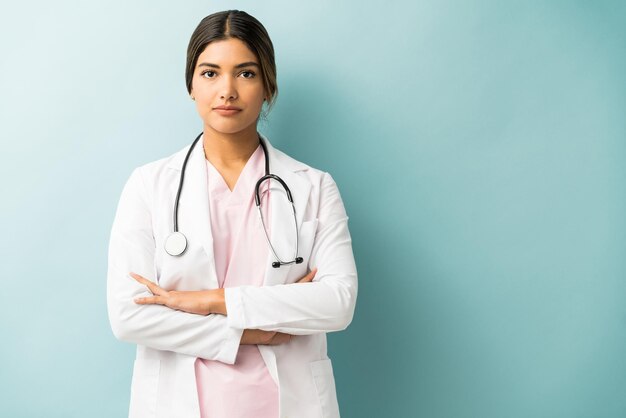 Professionnel de la santé attrayant en uniforme debout avec les bras croisés sur fond isolé