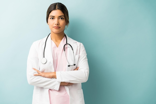 Professionnel de la santé attrayant en uniforme debout avec les bras croisés sur fond isolé