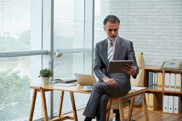 Professionnel travaillant avec tablette numérique dans son bureau écologique assis sur le bureau en bois