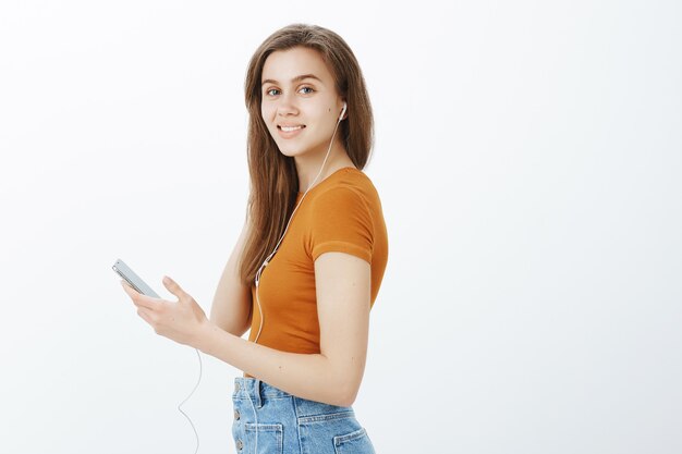 Profil de la belle femme au casque, tenant le smartphone et tourner la tête avec le sourire