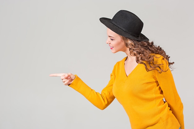 Le profil de la fille émotionnelle au chapeau sur mur gris