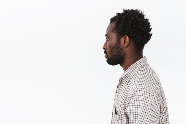 Profil tourné homme barbu afro-américain aux cheveux courts bouclés debout sur fond blanc avec casual