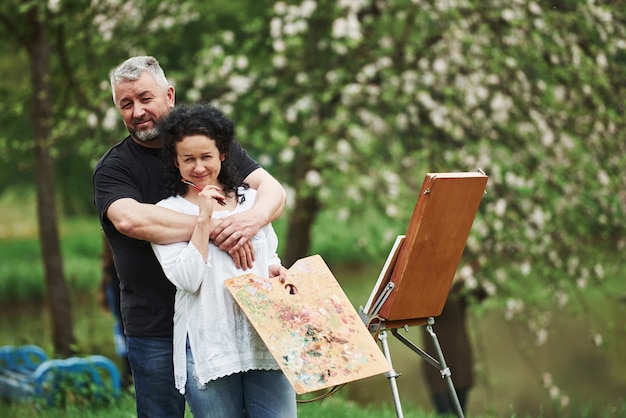 Profiter du week-end. Couple d'âge mûr ont des journées de loisirs et travaillent ensemble sur la peinture dans le parc