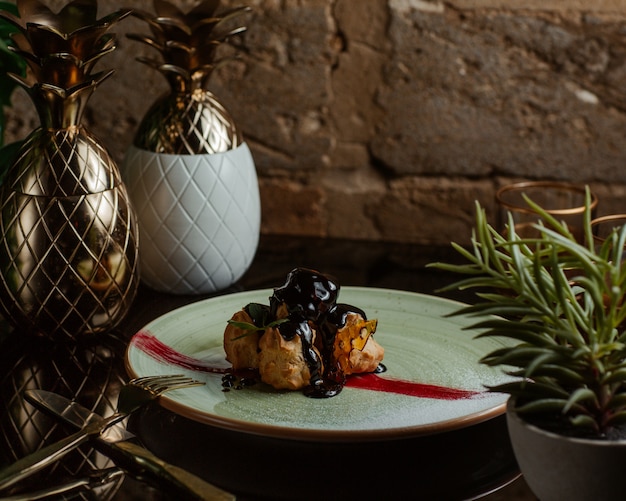 Photo gratuite profiteroles à la sauce au chocolat à l'intérieur d'une assiette blanche.