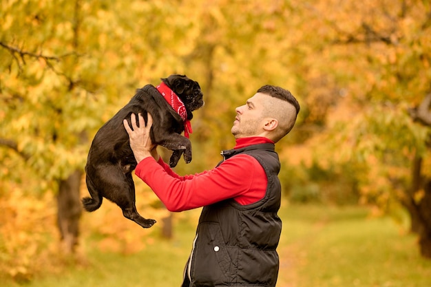 Un propriétaire d'animal avec son ami. Un homme debout dans le parc et tenant son chien mignon