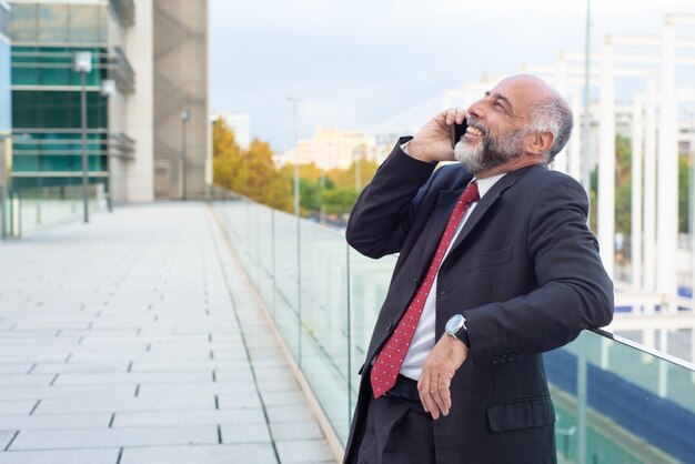 Propriétaire d'entreprise mature détendue joyeuse parler sur téléphone portable