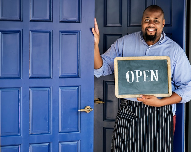 Photo gratuite un propriétaire de petite entreprise joyeux avec une enseigne ouverte