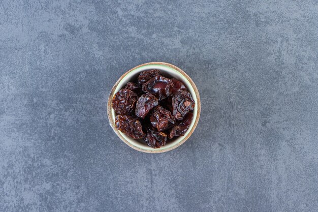 Prune séchée dans un bol sur une planche sur la surface en marbre