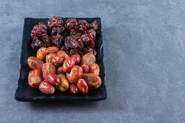 Prune séchée et oleaster sur une assiette, sur le fond de marbre.