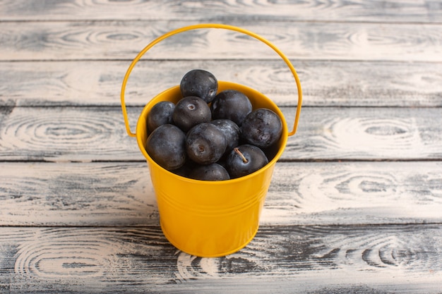 Photo gratuite prunellier aigre frais à l'intérieur du panier jaune sur bois gris