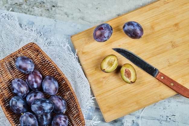 Prunes entières et demi-coupées mûres sur planche de bois. Photo de haute qualité