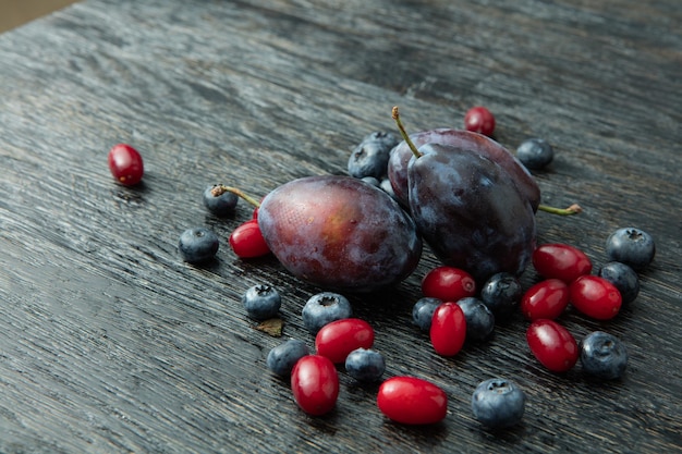 Photo gratuite prunes fraîches et baies sur une table en bois sombre