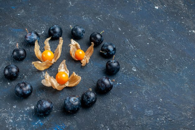 Prunes fraîches bordées en cercle sur un bureau sombre