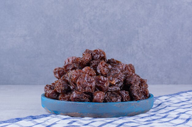 Prunes de griottes séchées à l'intérieur d'un plat isolé sur une surface en béton