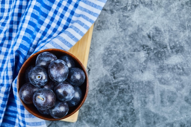 Photo gratuite prunes de jardin sur bol sur marbre avec nappe.