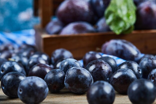 Prunes de jardin éparpillées sur une table en bois.