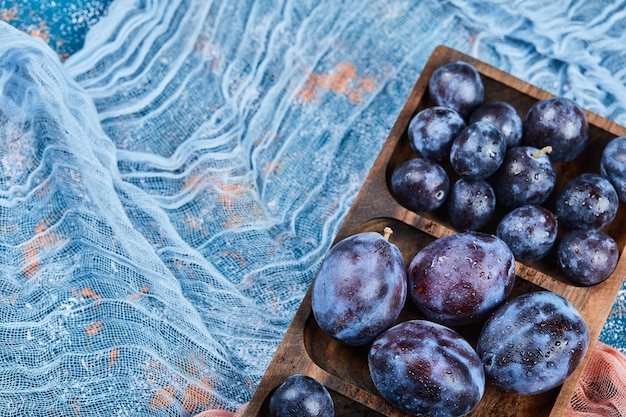 Photo gratuite prunes de jardin sur plateau en bois avec nappe