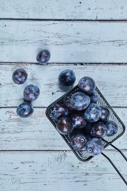 Photo gratuite prunes de jardin sur table bleue.