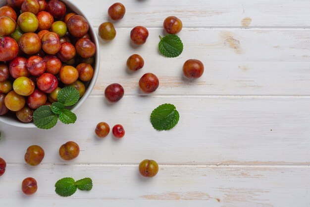 Photo gratuite prunes mûres sur la surface en bois blanche.