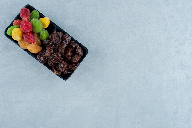 Prunes noires séchées et cerises multicolores sur un plateau. photo de haute qualité