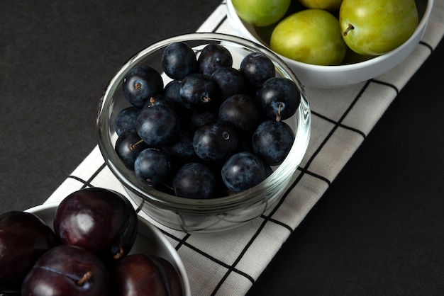 Prunes noires et vertes dans une soucoupe en céramique blanche