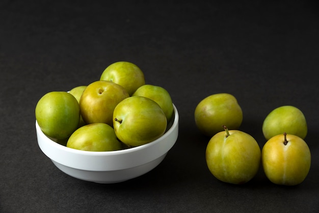 Prunes vertes dans une soucoupe en céramique blanche