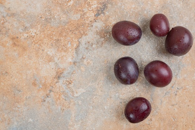 Prunes violettes mûres sur fond de marbre.