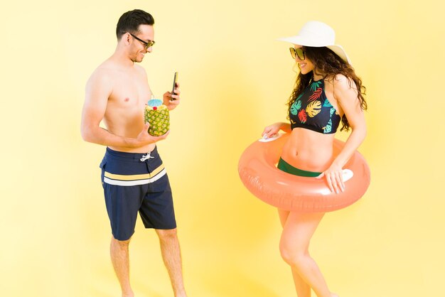Publier cette photo sur les réseaux sociaux. Bel homme prenant une photo avec un smartphone de sa petite amie en bikini pendant les vacances d'été ensemble