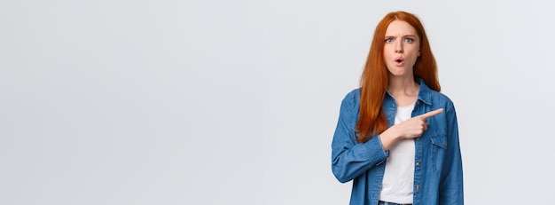 Photo gratuite qu'est-ce que c'est que cette femme autoritaire rousse tendue et folle frustrée pointant vers la droite en attendant l'explication