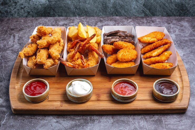 Photo gratuit quatre boîtes de pépites avec du fromage de crevettes au poulet et du poisson avec quatre sauce