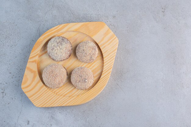 Quatre boules de truffes savoureuses placées sur une assiette en bois.