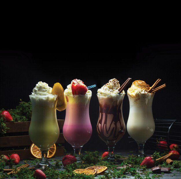 Quatre différents smoothies cocktail avec de la crème laiteuse sur le dessus