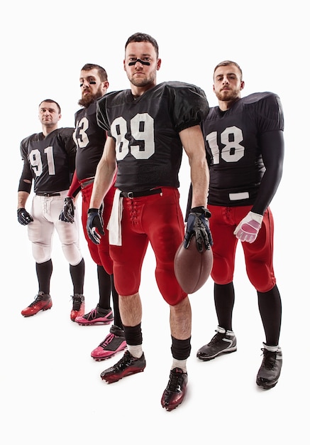 Photo gratuite les quatre hommes de fitness caucasiens en tant que joueurs de football américain posant sur toute la longueur avec un ballon sur blanc
