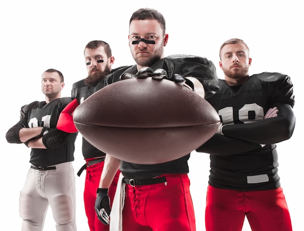 Photo gratuite les quatre hommes de fitness caucasiens en tant que joueurs de football américain posant sur toute la longueur avec un ballon sur blanc