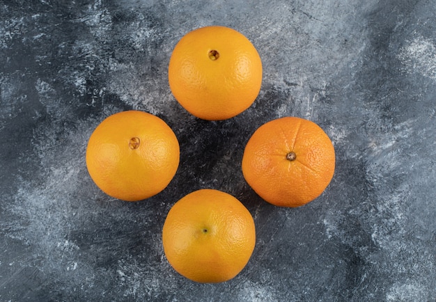 Quatre oranges savoureuses sur table en marbre.