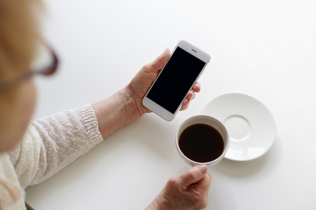 Quelqu'un utilise son téléphone tout en prenant une tasse de café