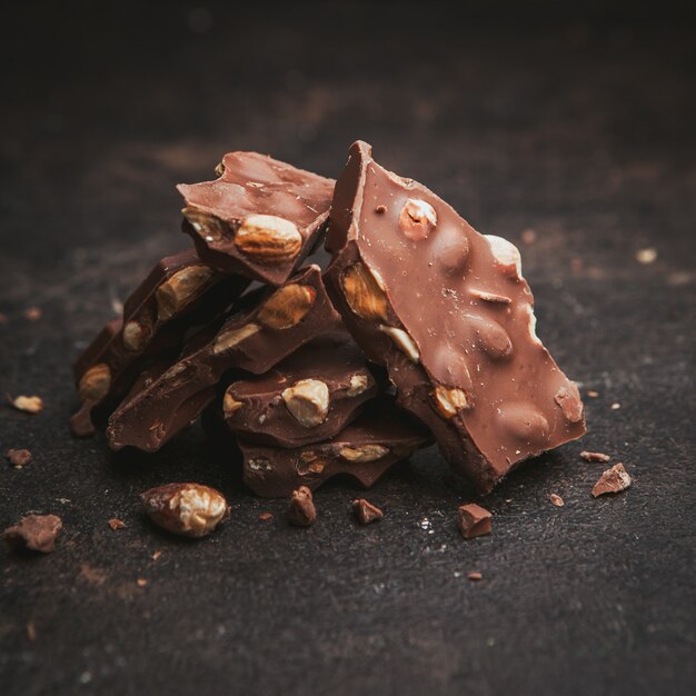 Quelques amandes au chocolat sur fond brun texturé, gros plan.